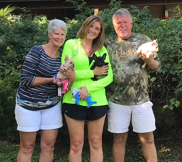 Longtime Must Be Frenchies family holding three French Bulldog puppies during their first visit in 2018